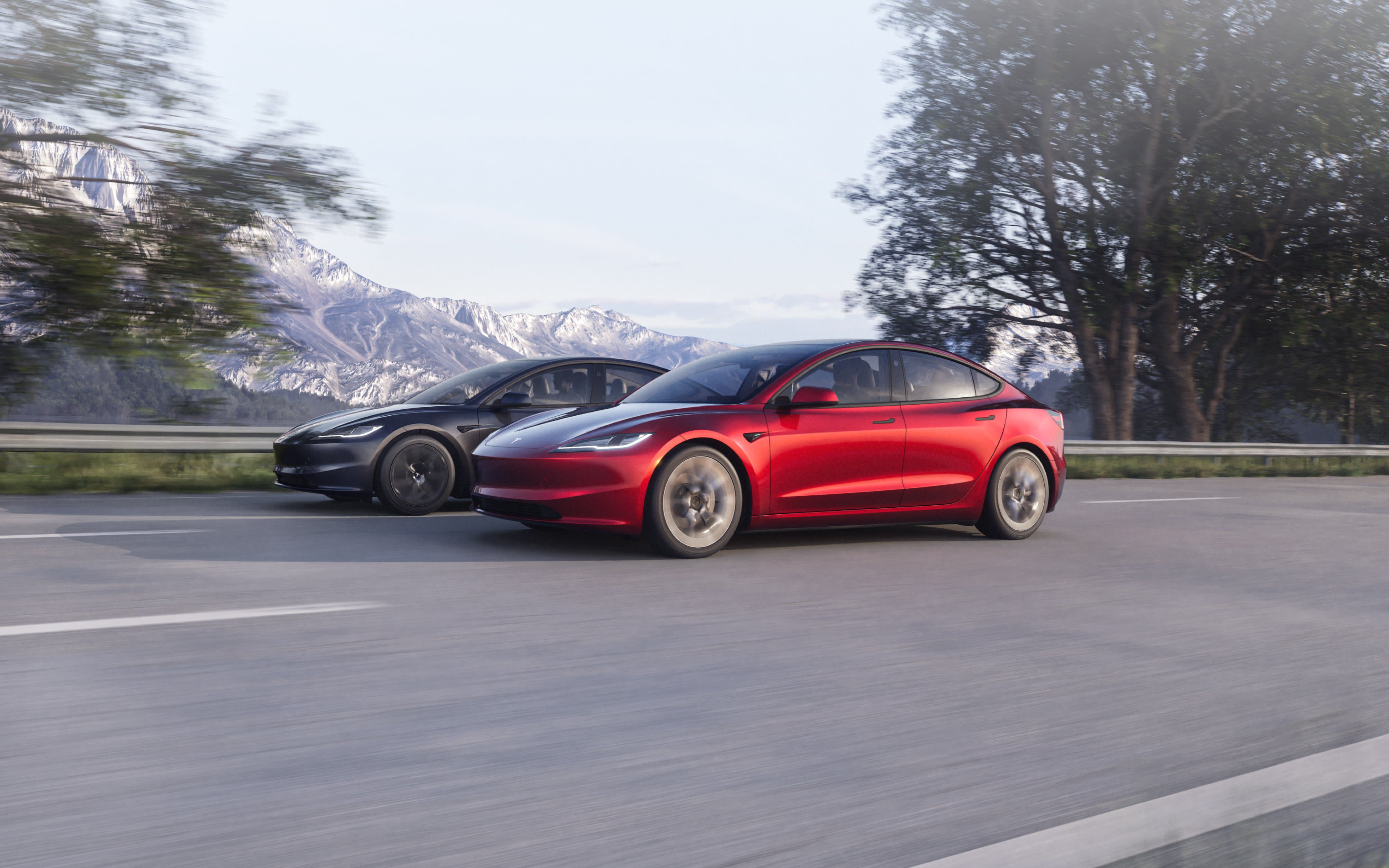 Red Model 3 driving down a lakeside road